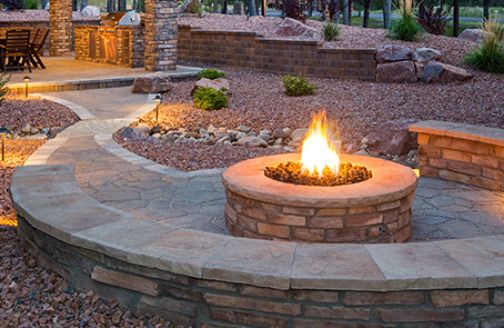 Lit stonework firepit with built-in wrap-around bench.