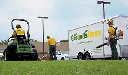 Three Grounds Guys employees performing lawn cleanup work.