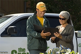 The Grounds Guys service professional reviewing a tablet with a customer.