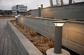 A pathway framed by a three-tiered stone retaining wall system, with column lights installed on each level.