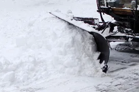 A snow plow moving snow off a road.