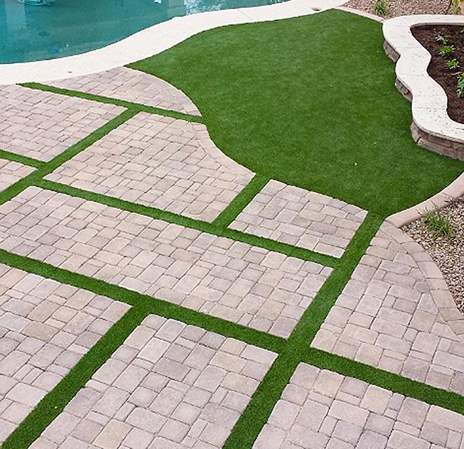 Artificial turf installed next to a pool and in between stones.