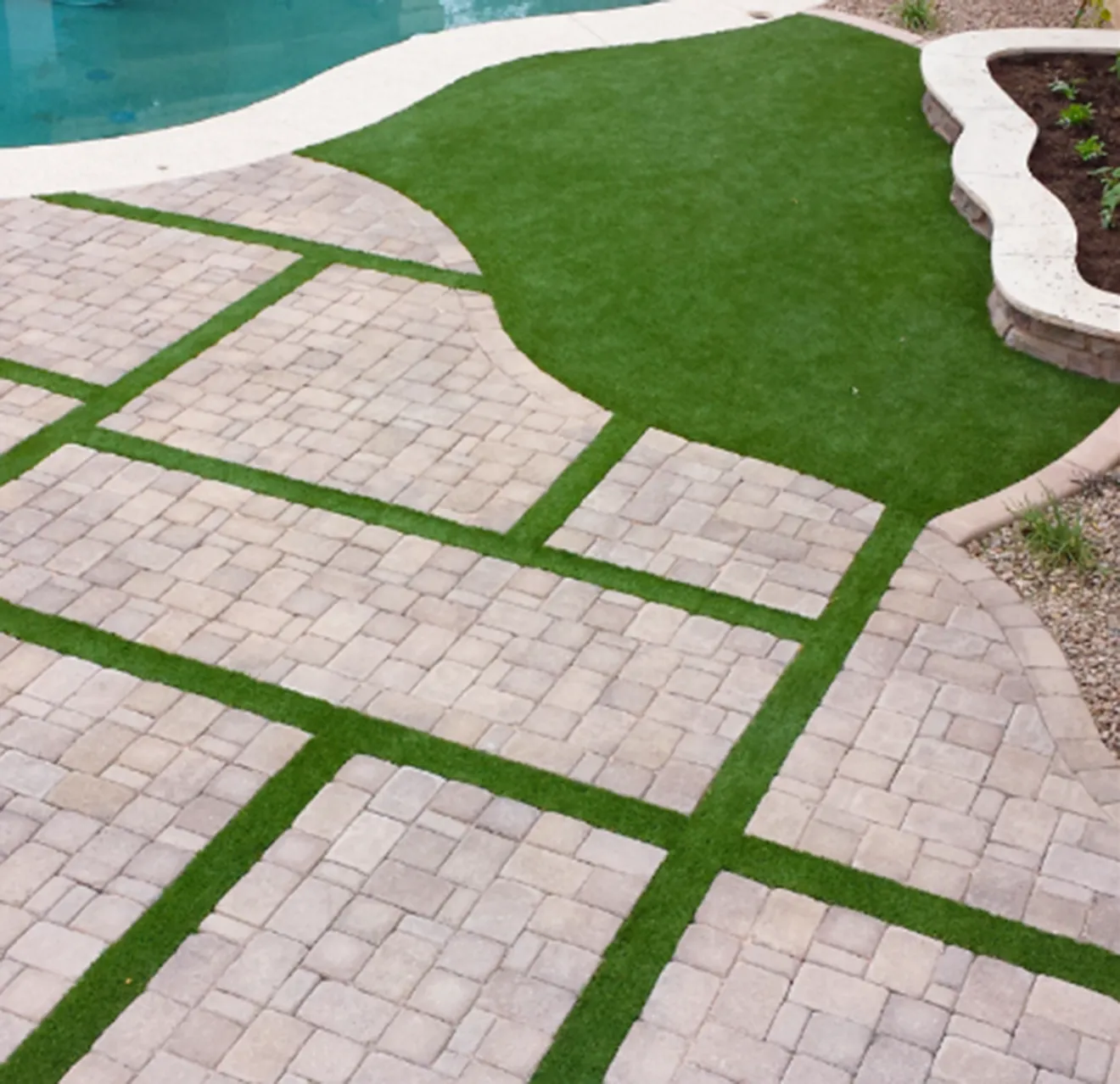 Artificial turf installed next to a pool and in between stones.