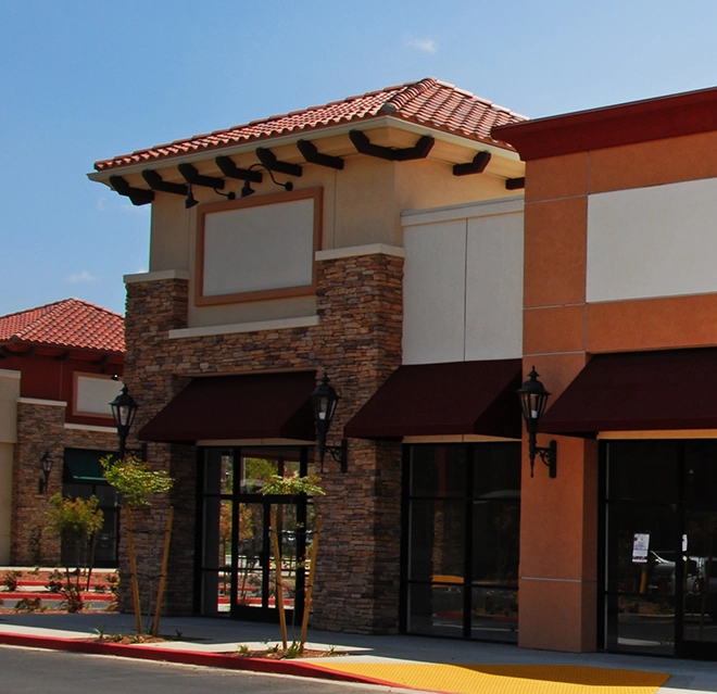 A two-story commercial building in a strip mall, with gutters visible.