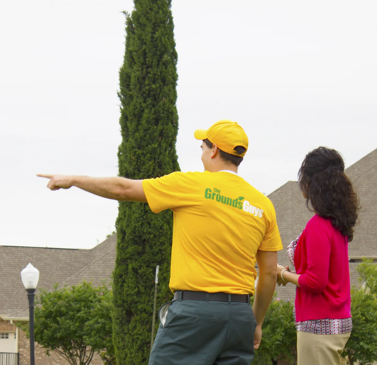 The Grounds Guys service professional pointing out a landscaping feature to a customer.