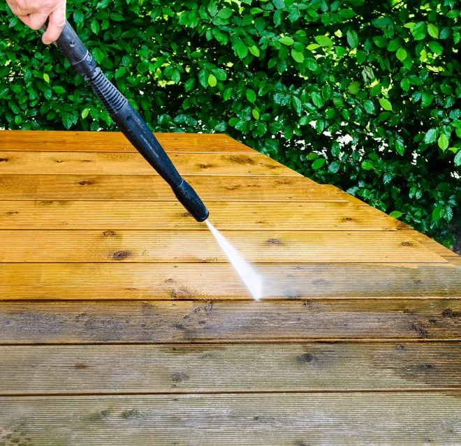 A wood deck being cleaned by pressure washing.