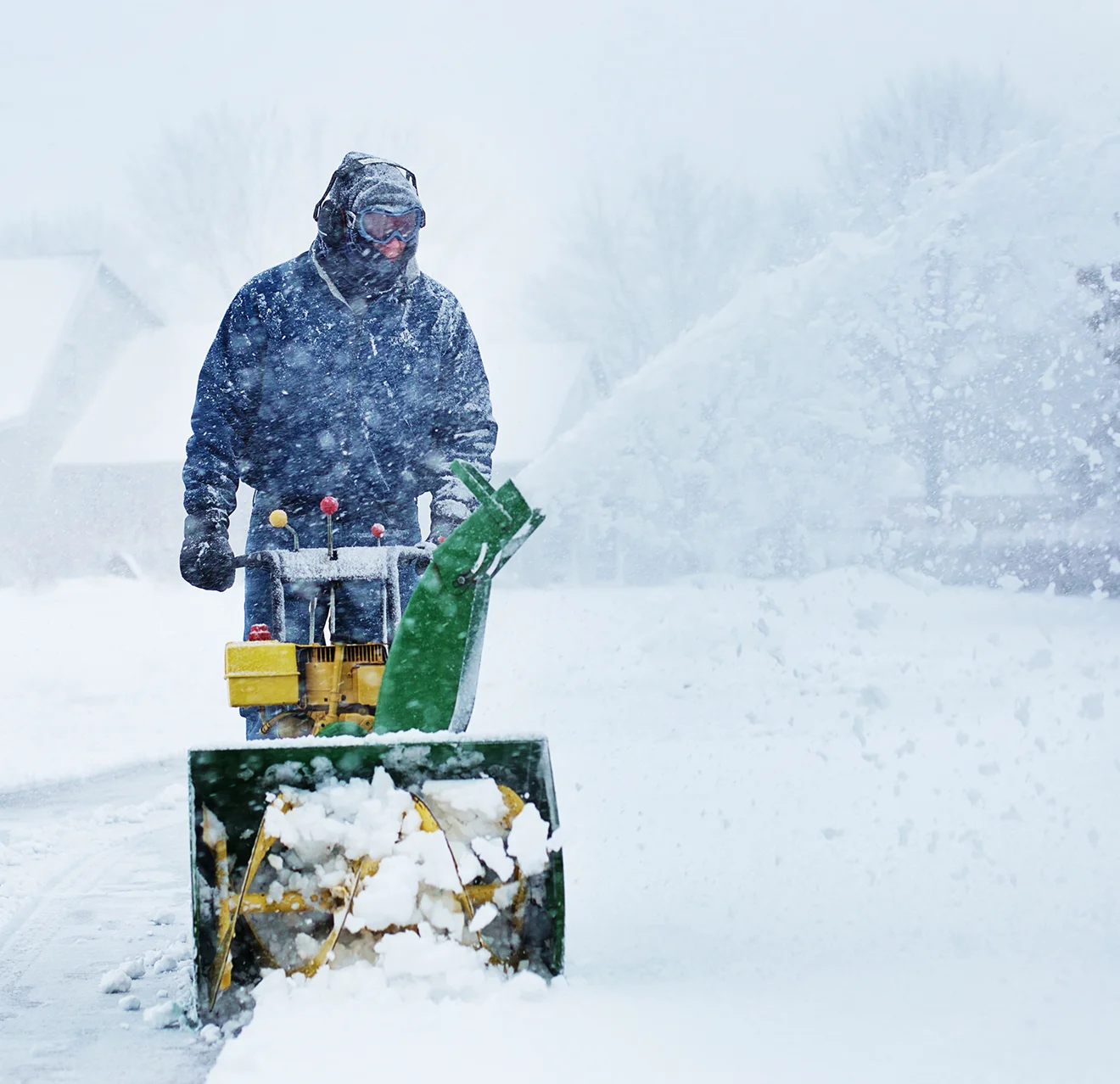 The Grounds Guys service professional using a snow blower during a snowstorm.