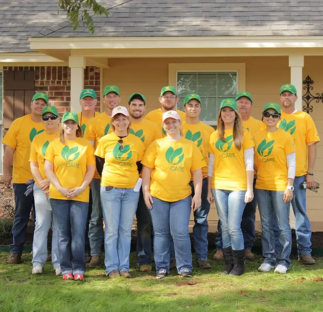 A team of The Grounds Guys service professionals standing in front of a house.