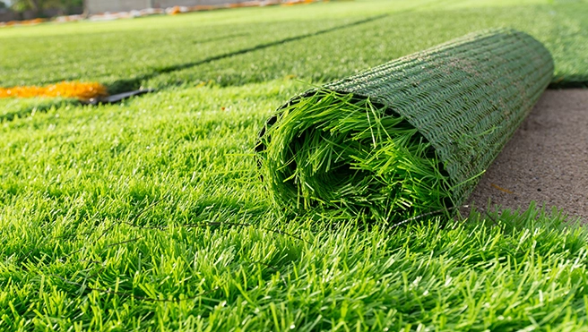 A lawn covered in artificial turf, with one roll only partially installed.