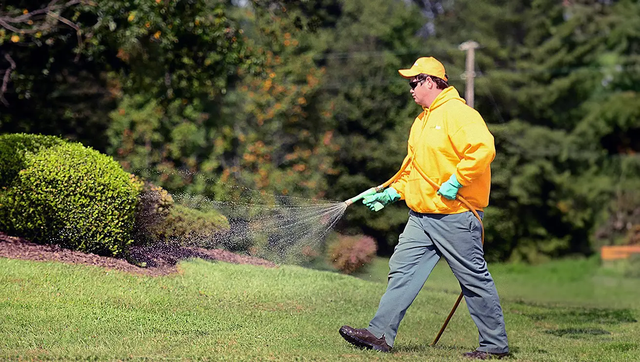 The Grounds Guys service professional watering a lawn.