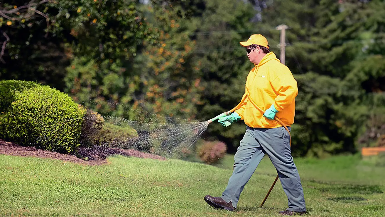 The Grounds Guys service professional spraying a lawn with fertilizer.