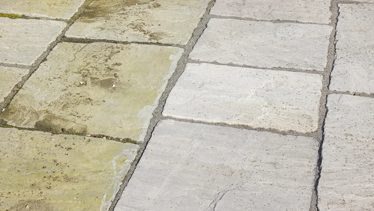 On the left, stone pavers with dirt and mildew; on the right, clean, pressure-washed stone pavers.