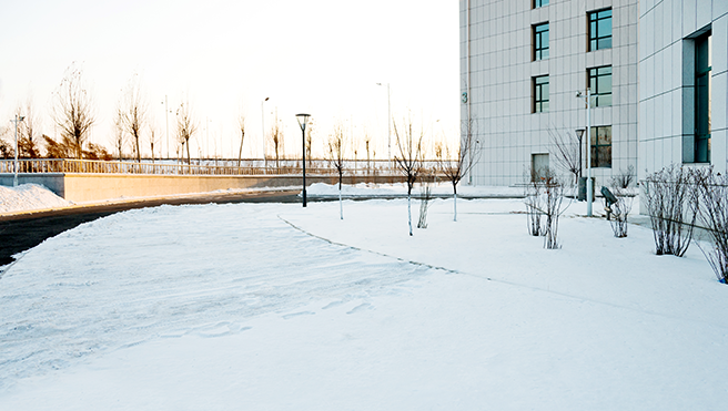 The street outside an office building covered in snow, about to be plowed.