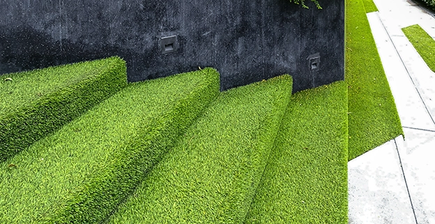 The exterior steps of a building covered in artificial turf, or synthetic grass.