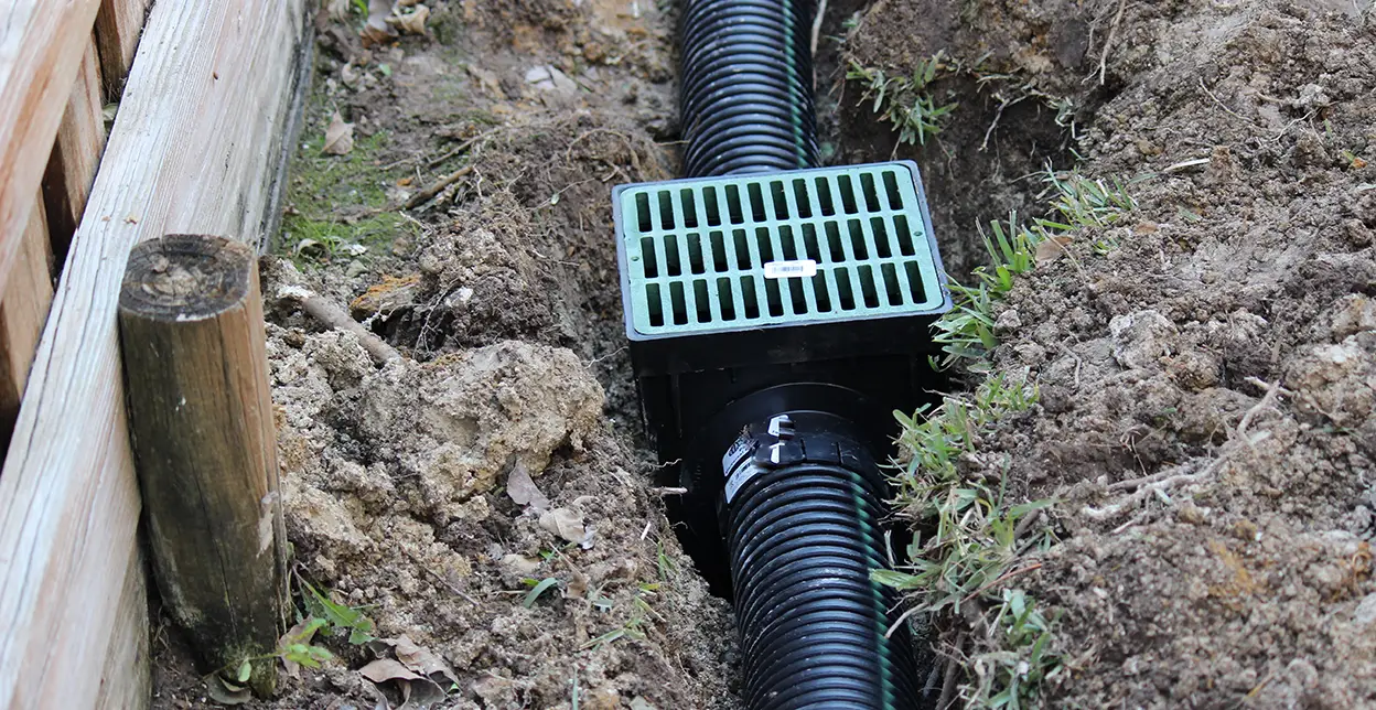 A drain pipe and basin installed in soil.