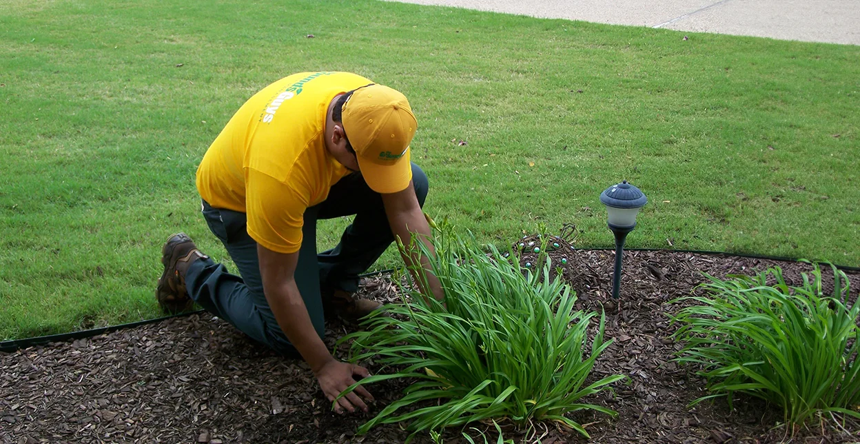 The Grounds Guys service professional tending to a mulch bed.