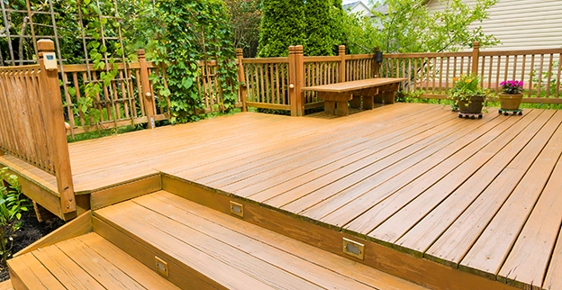 A wood deck with built-in lighting and a trellis with plants.