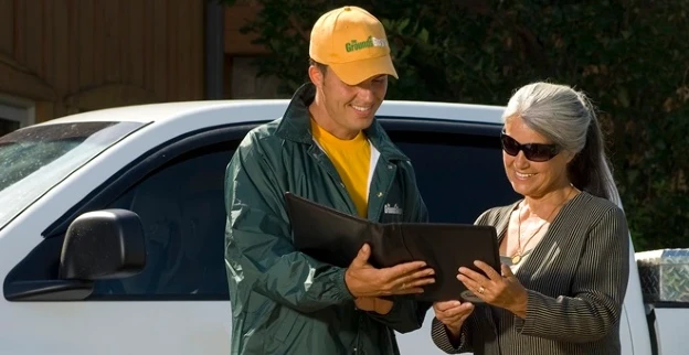 The Grounds Guys service professional reviewing a tablet with a client.