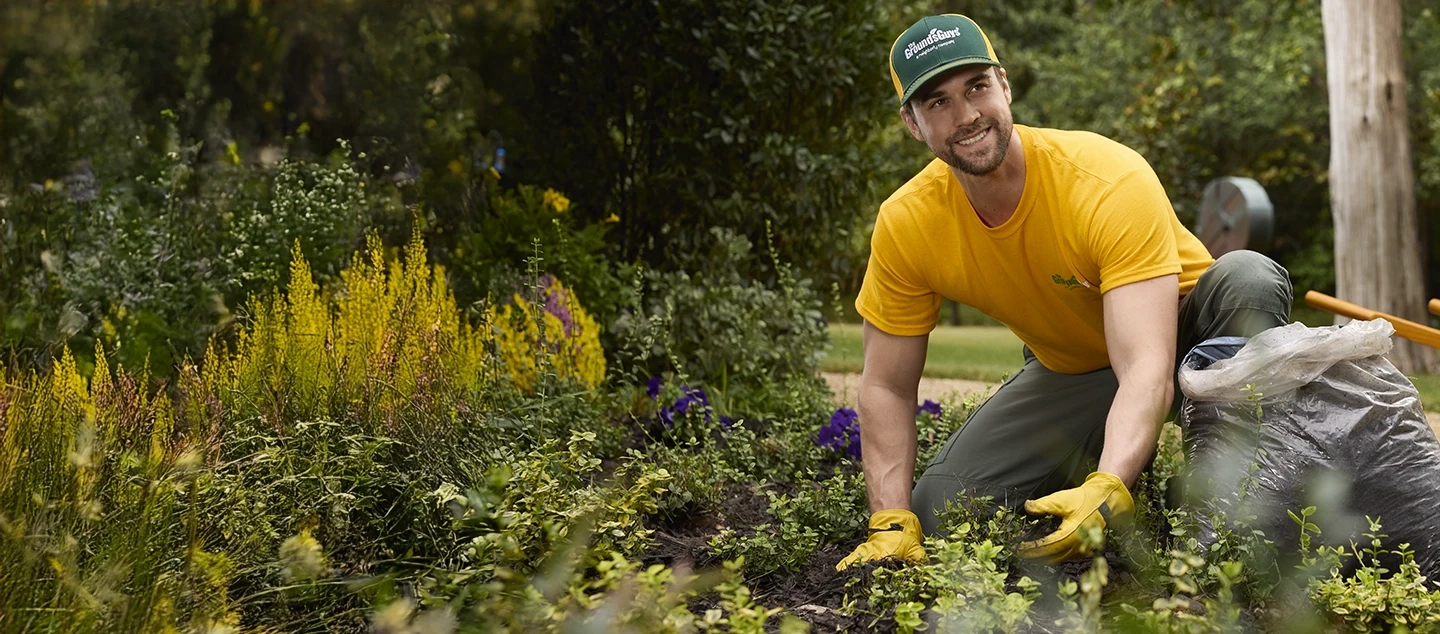 The Grounds Guys service professional installing mulch in a flower bed.