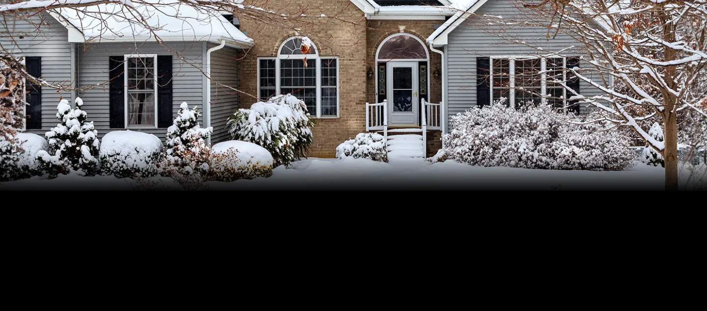 Freshly fallen snow covering the yard and roof of a single-family home.