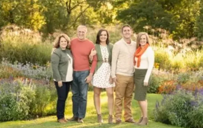 The owners and family of The Grounds Guys of New Lenox - Orland Park standing next to flower beds.