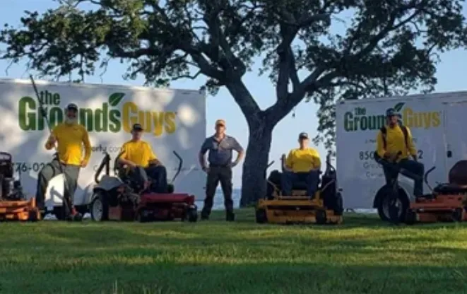 The Grounds Guys of Pensacola team standing under a tree.