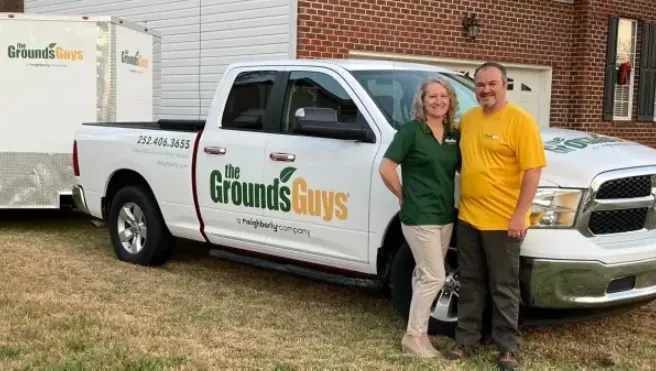 The Grounds Guys of Rocky Mount owner Phil Broomell and his wife Liz in front of a branded truck.