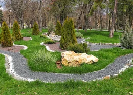 A circular path, shrubs, and a wooded area on a commercial property.