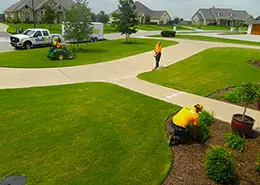 Three Grounds Guys service professionals mowing and edging a front lawn.