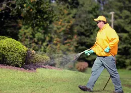 The Grounds Guys service professional spraying fertilizer on a lawn.