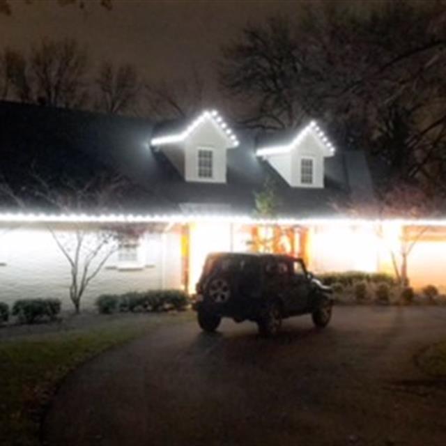 A car in front of the house with outdoor lights.