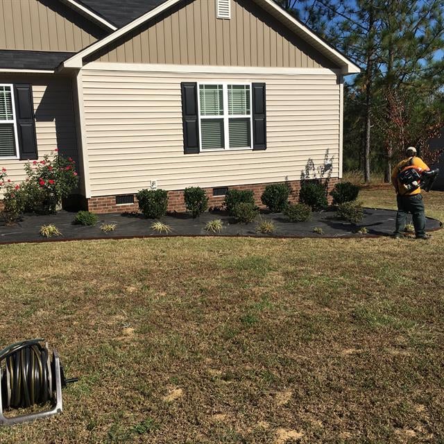 A ground guy cutting the grass in a garden.