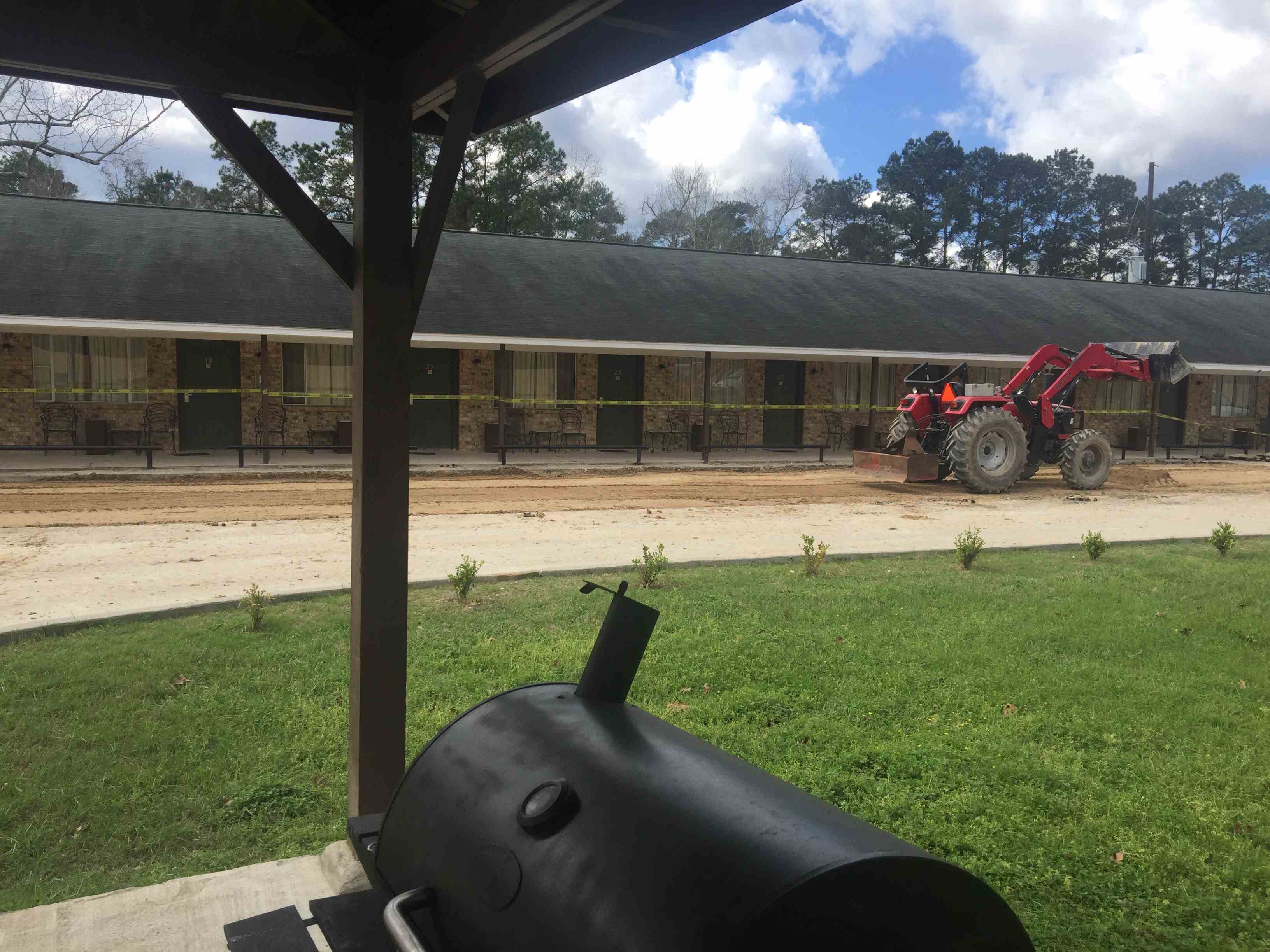 Excavator on concrete plot with yard in foreground