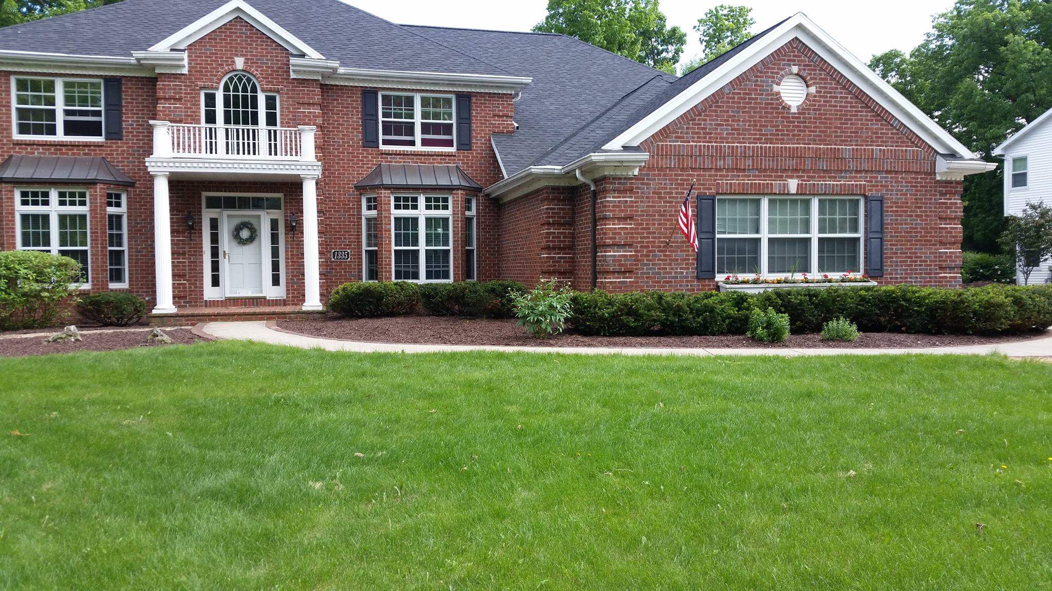 Front of brick house, with well manicured lawn and planters