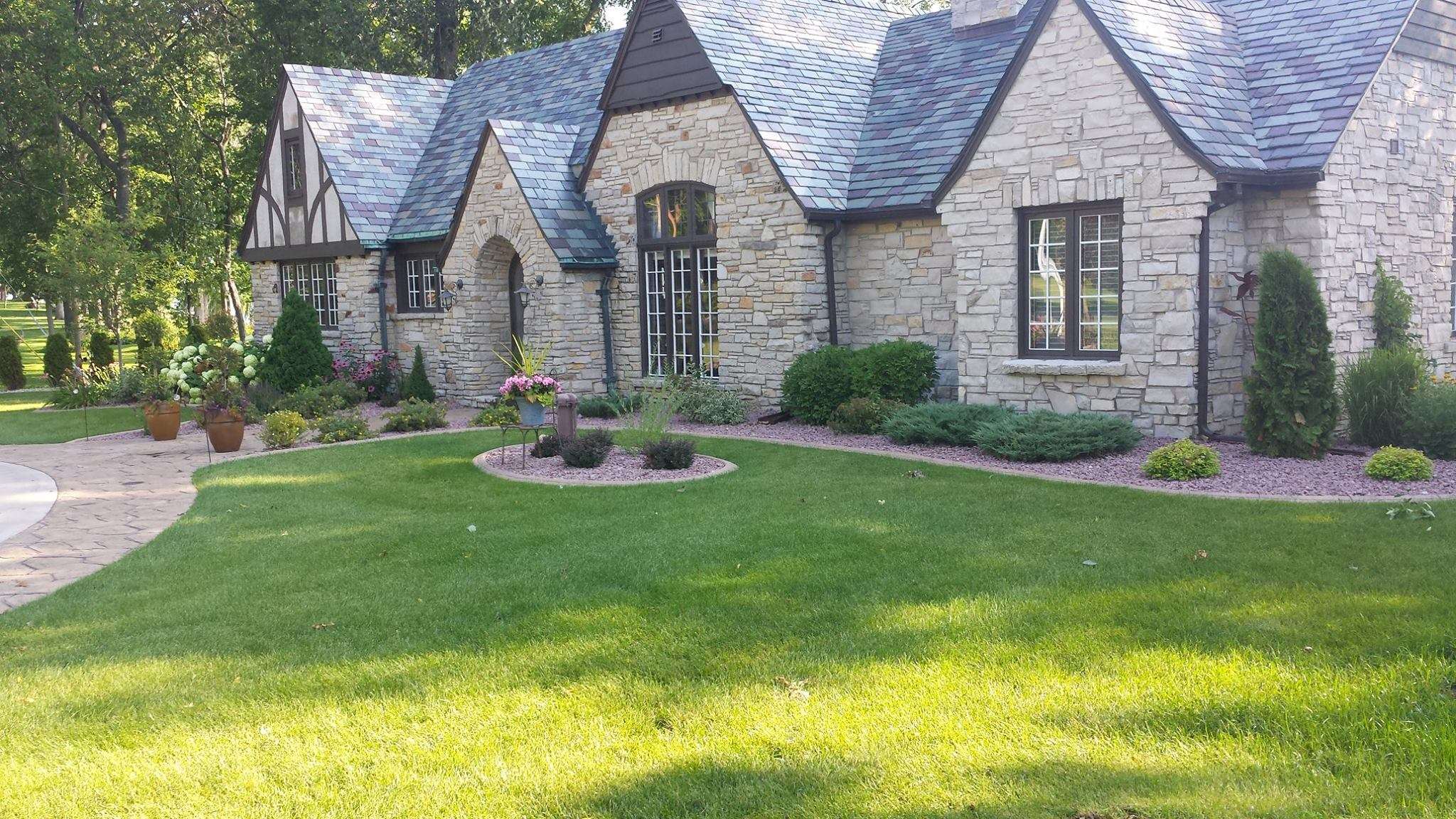 Well manicured lawn and planters surrounding stone house