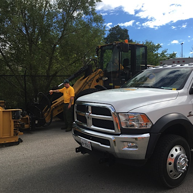 Ground guys doing work using machinery with a truck near it.