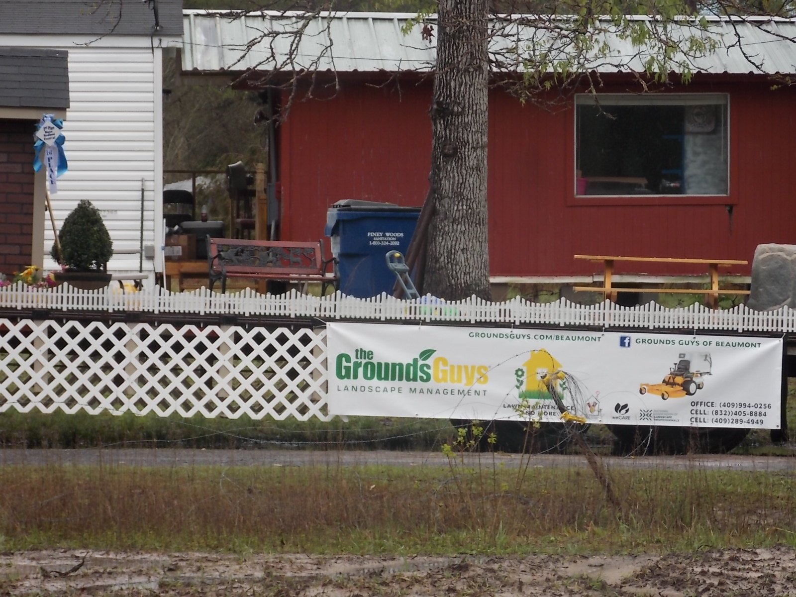 Grounds Guys banner on fence in front of red house