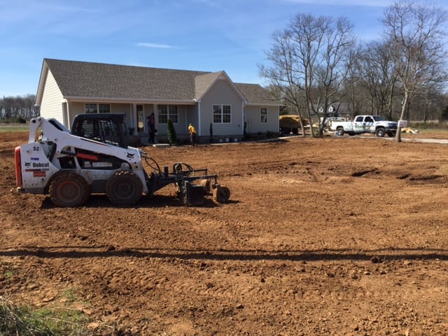 Heavy machinery being used to level dirt yard. 