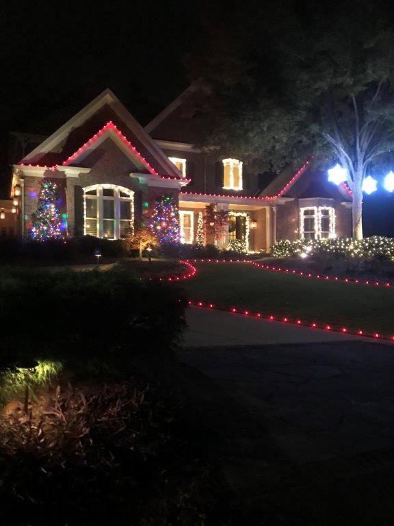 Red string lights on house and lining lawn 