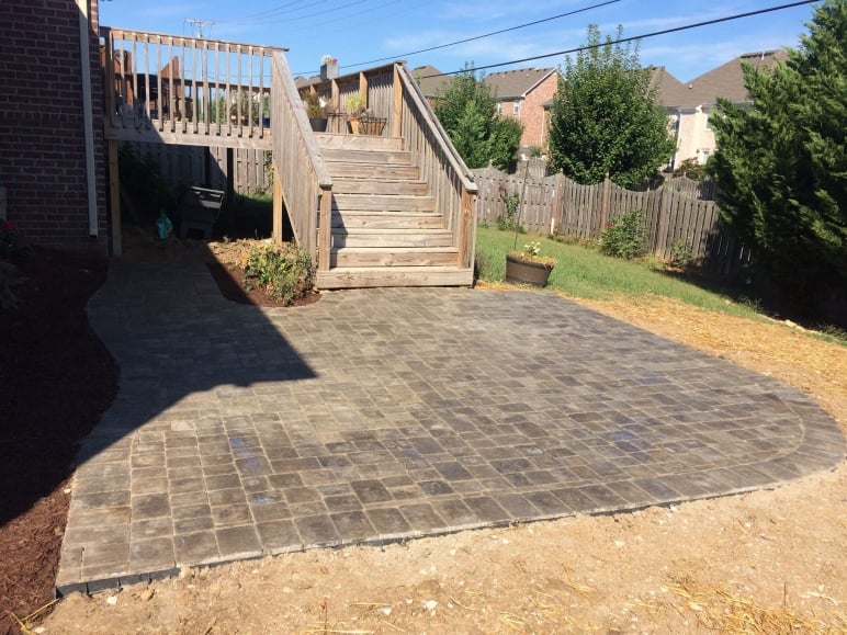 Stone patio with wooden stairs to deck.