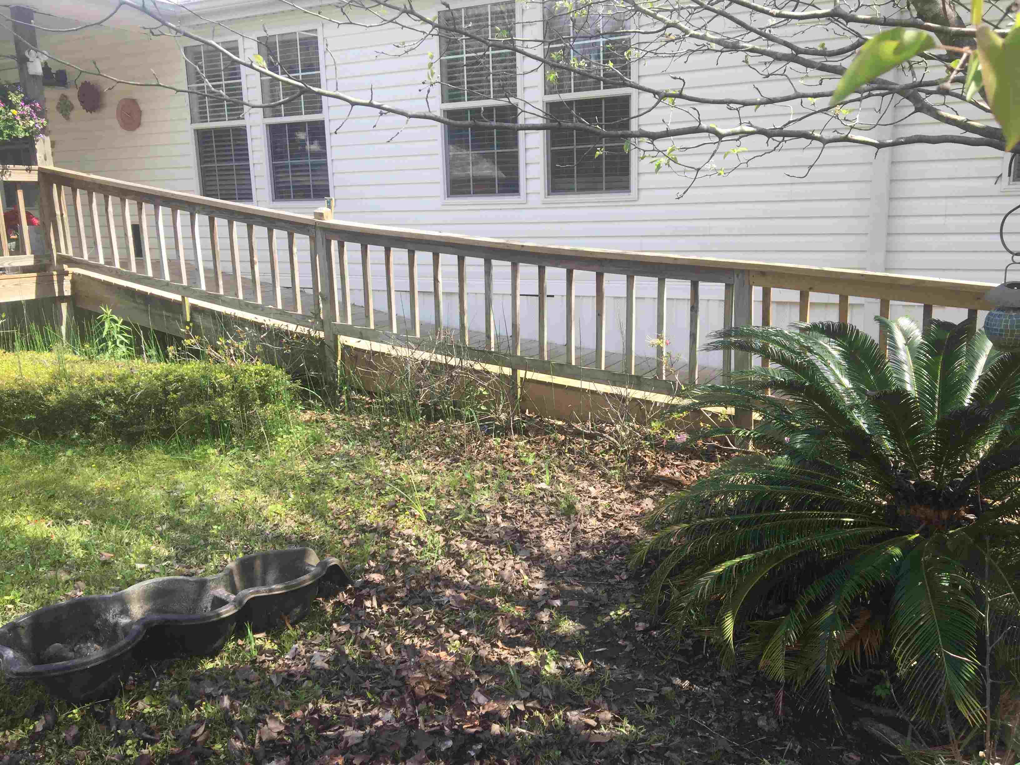 Tan fence in front of white house with yard