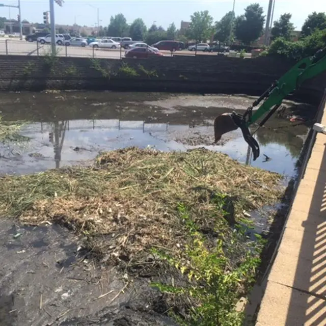 backhoe cleaning debris from a commercial pond