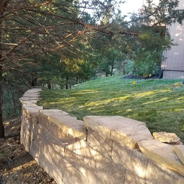 a stone retaining wall with a manicured yard