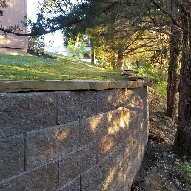 retaining wall with trees and manicured lawn