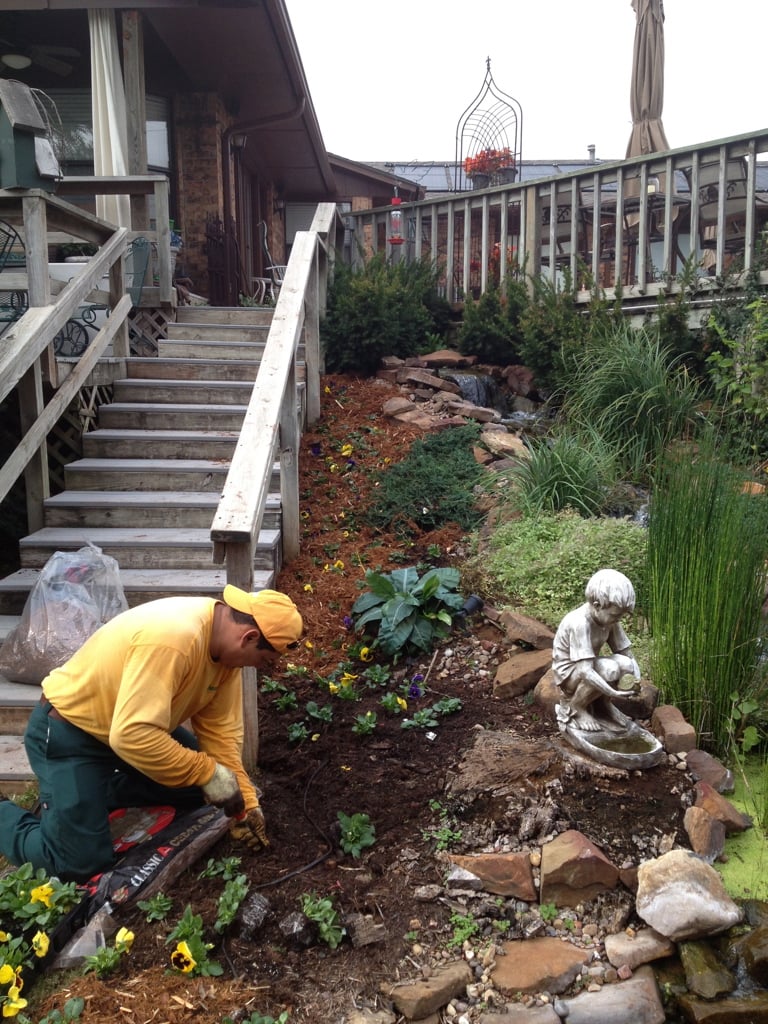 The Grounds Guys putting mulch down around flowers