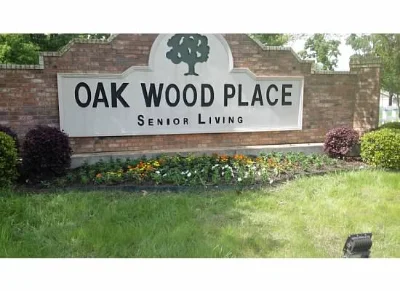 The Oak Wood Place Senior Living Sign complete with flowers, shrubbery, and lighting