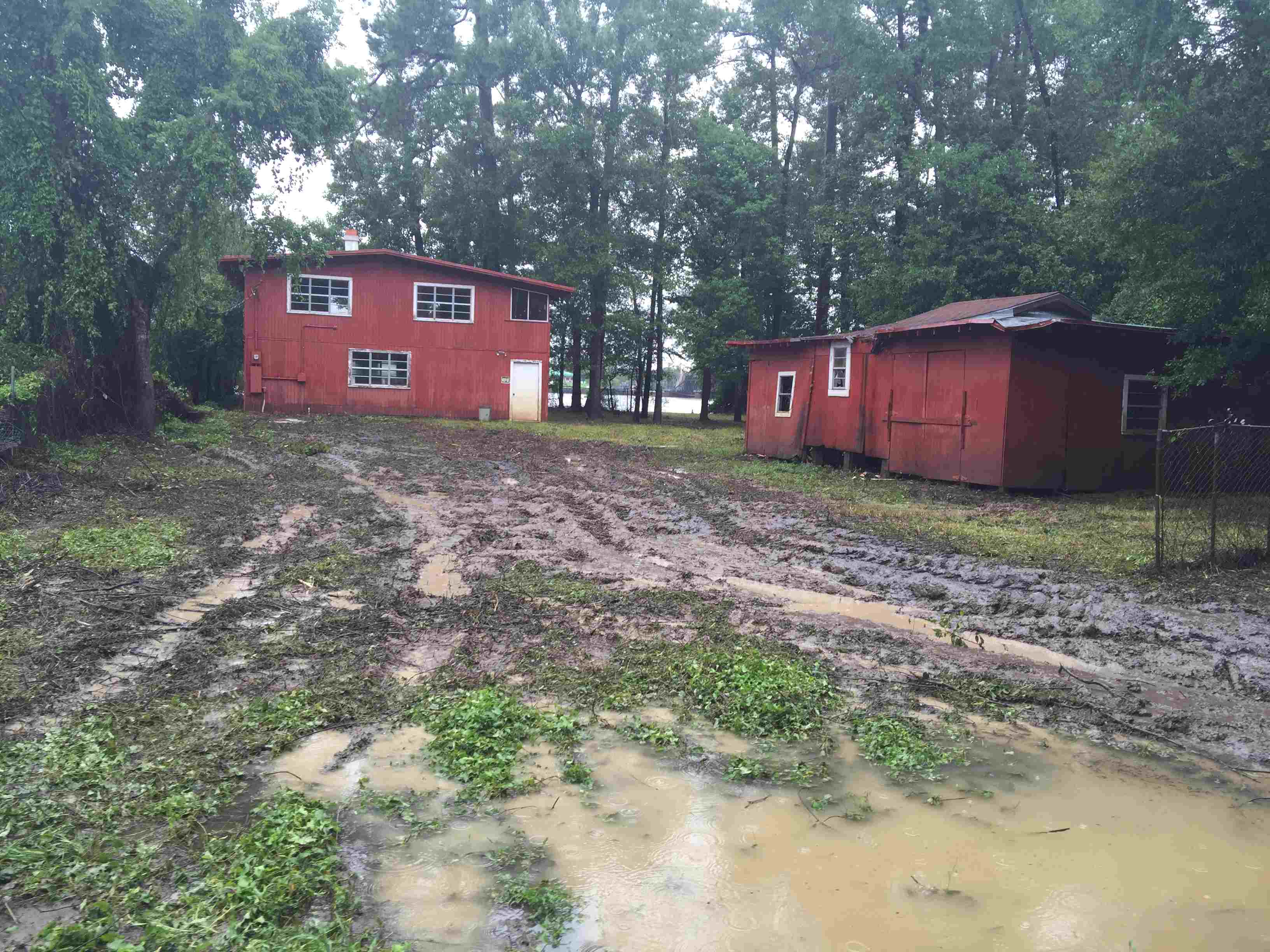 Two red houses in a forest with muddy yard