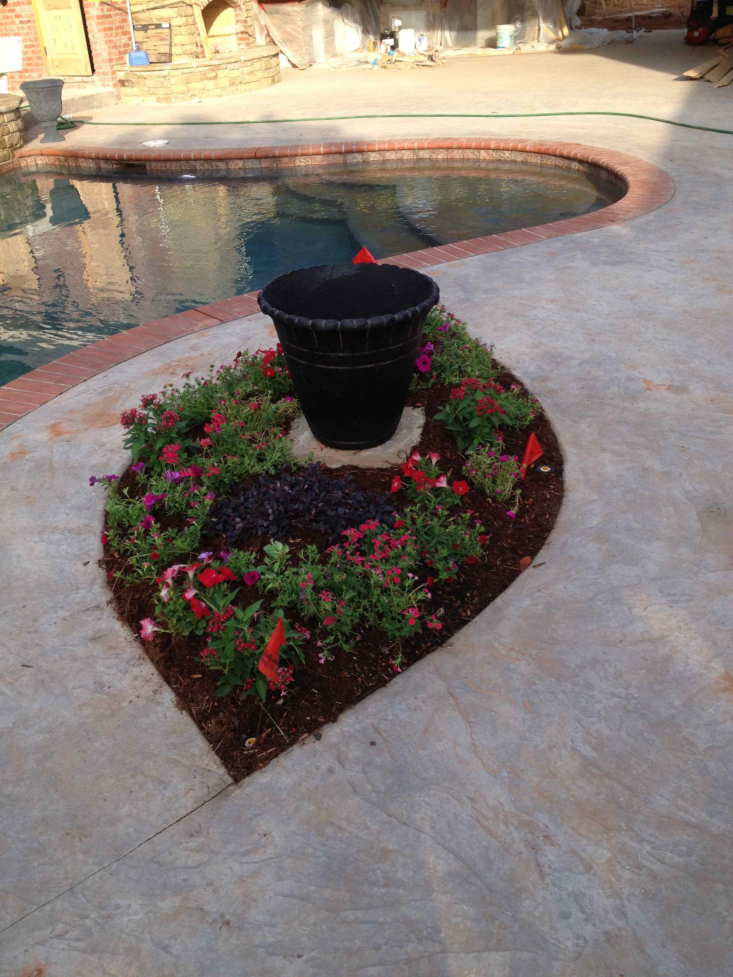 diamond shaped planter with flowers next to pool. 