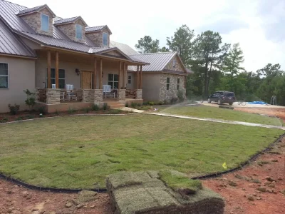 dirt yard in front of newly constructed stone house.