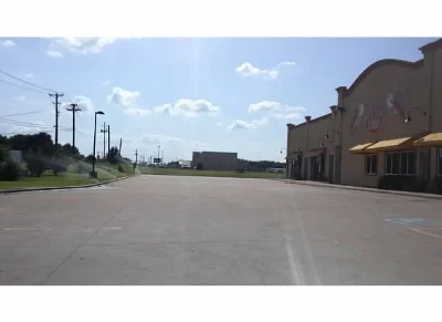 paved parking lot with green grass and sprinklers